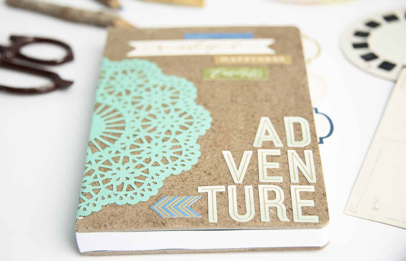 Image of a notebook decorated with cut-out patterns and the word "Adventure".