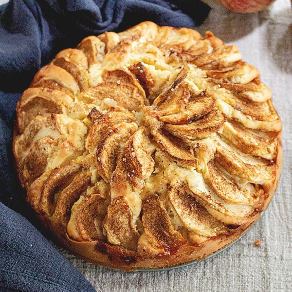 Photo of a German apple cake, with slices of apple decoratively arranged on the top.