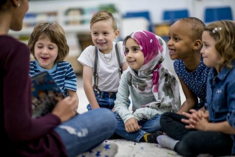 Image of children gathered around a librarian reading a picture book.