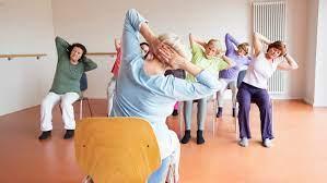 Image of a chair yoga class, with participants stretching their arms while seated.