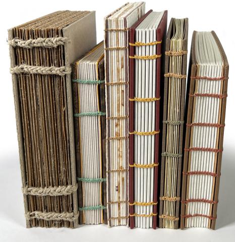 Stack of hand-sewn books with muted colors.