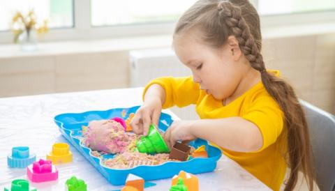 Girl playing with sand and beads