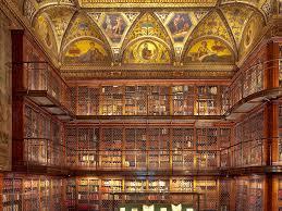 Interior of the Morgan Library, a classic dark-wood, multi-level library lit with soft golden lamps.