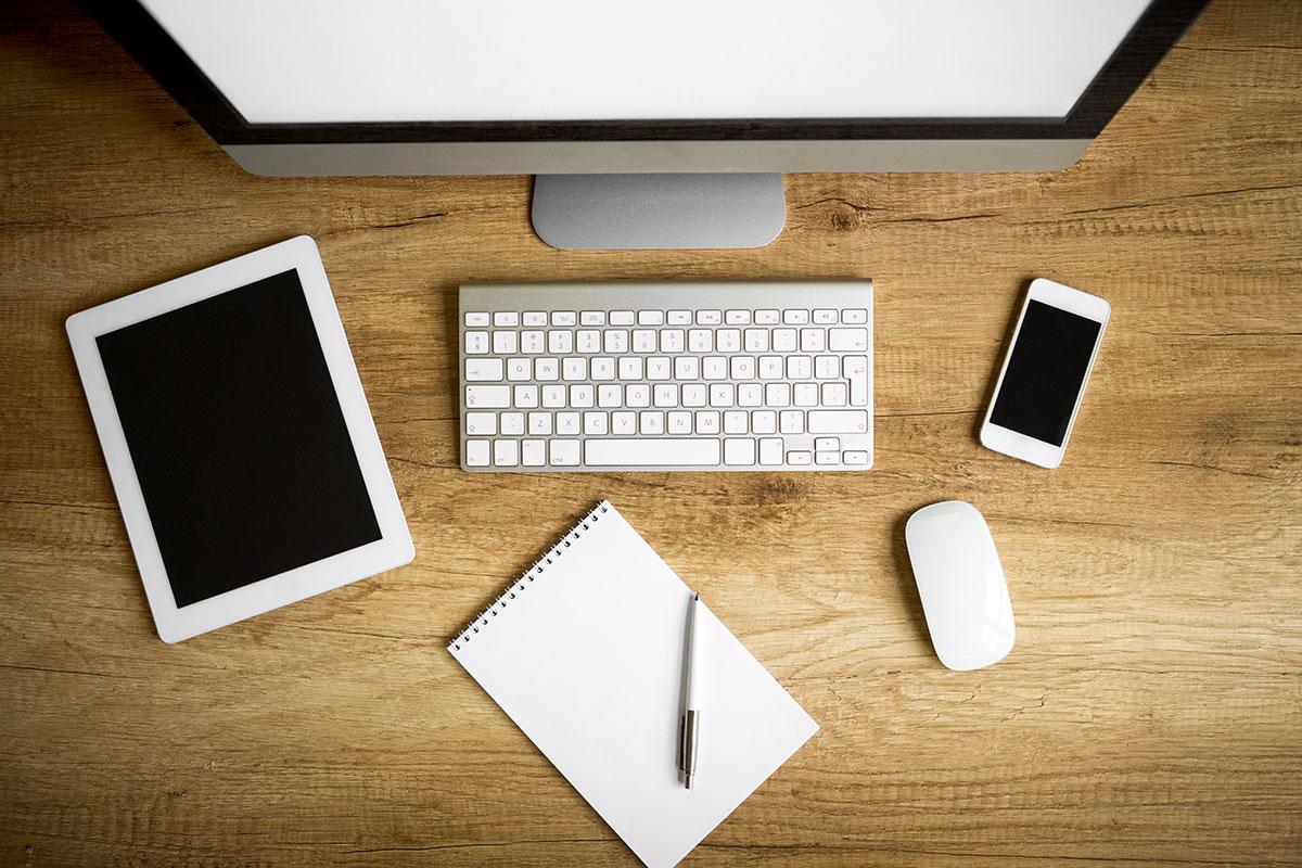 Image of a computer screen, keyboard, tablet, and smartphone.