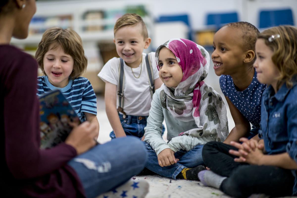 Image of children gathered around a librarian reading a picture book.