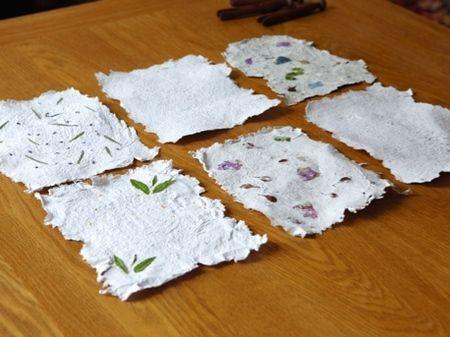 Home made paper with colorful seeds on a table.