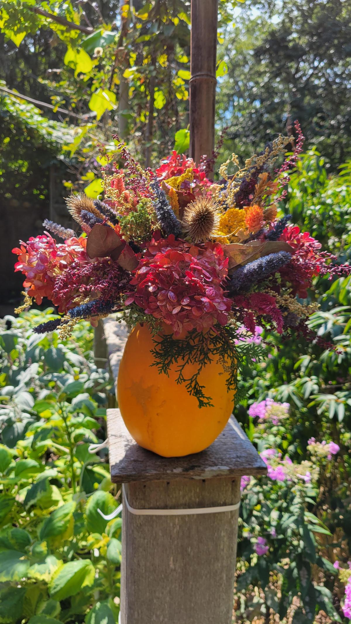 Picture of a pumpkin used as a vase for fall flowers.